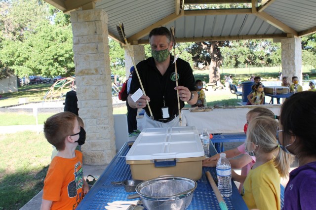 Chris Leach, a conservation biologist, shows arrows at the Archaeology station during the U.S. Army Environmental Command Nature Walk held for about 140 kindergarteners from the Fort Sam Houston Elementary School.