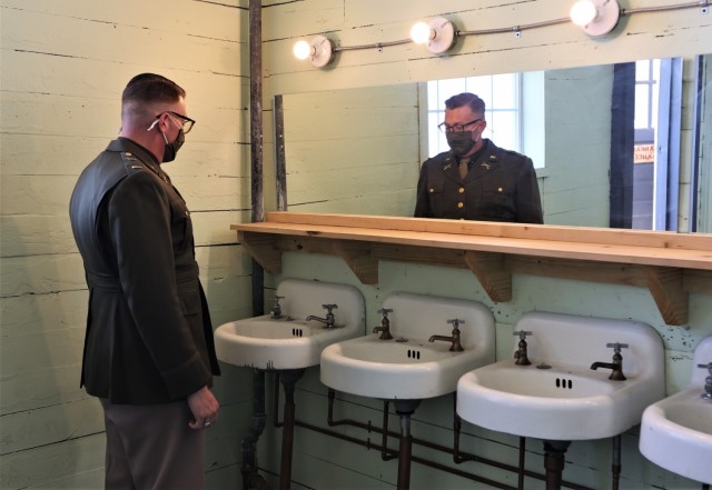 A visitor in uniform walks through the barracks latrine, which was restored to its original condition.