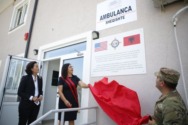 U.S. Ambassador to Albania Yuri Kim looks on as Patos Mayor Rajmonda Balilaj and Chief of the Office of Defense Cooperation at the U.S. Embassy in Tirana Lt. Col. Erol Munir, unveil signage at a ceremony at the two-story kindergarten and health...
