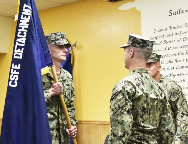 Navy Lt. Joshua Lamb, left, receives the colors from Navy Lt. Nicholas Gegg during the Navy Detachment’s change-of-charge ceremony Tuesday in Shields Hall.
