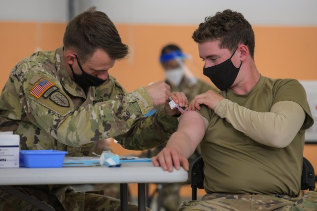 U.S. Army Staff Sgt. Paul Kovari, left, a medic with 2nd Cavalry Regiment, administers a COVID-19 vaccination to a fellow Soldier at the 7th Army Training Command&#39;s (7ATC) Rose Barracks, Vilseck, Germany, May 3, 2021. The U.S. Army Health Clinics at Grafenwoehr and Vilseck conducted a &#34;One Community&#34; COVID-19 vaccine drive May 3-7 to provide thousands of appointments to the 7ATC community of Soldiers, spouses, Department of the Army civilians, veterans and local nationals employed by the U.S. Army.