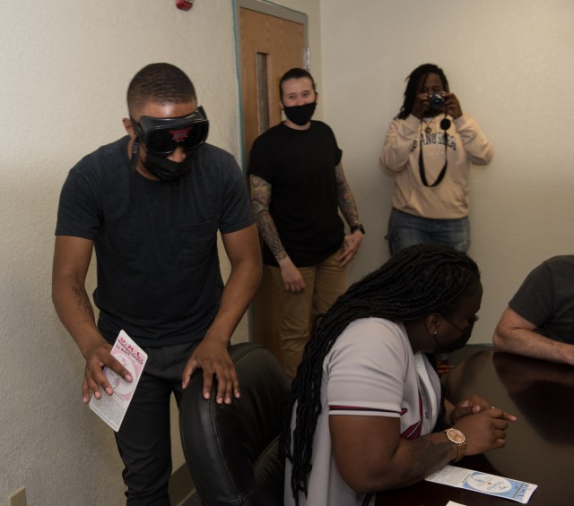 Pfc. Deandre Jones navigates the room wearing the ASAP "drunk goggles" during training May 10.  While simulating being impaired, the training aid helps the ASAP coordinator emphasize the importance of understanding the effects of alcohol.  (U.S. Army photo by Sgt. 1st Class Kelvin Ringold)