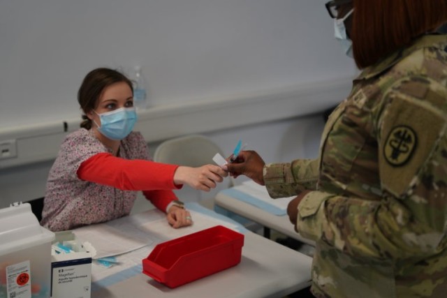 Breslin Gillis hands COVID-19 Vaccine to soldier. 