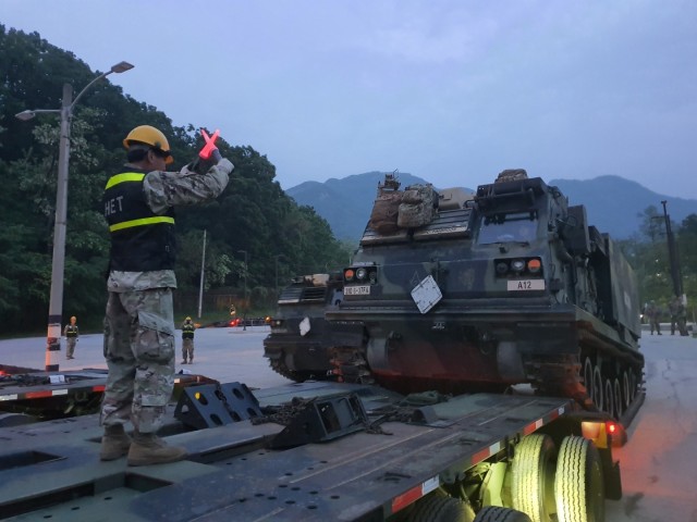 A member of the 7th KSC Company provides hand & arm signals to assist in loading a M2A2 Abrams Tank onto the Heavy Equipment Transportation (HET) Trailer.