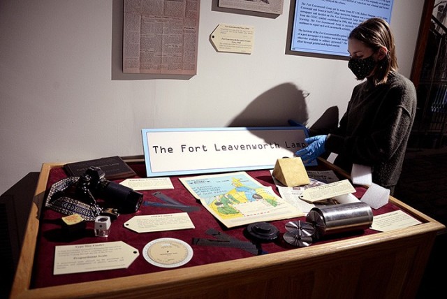Fayelee Overman, museum technician, rearranges items as she installs the “News at Fort Leavenworth” exhibit May 5 at the Frontier Army Museum. Photo by Prudence Siebert/Fort Leavenworth Lamp