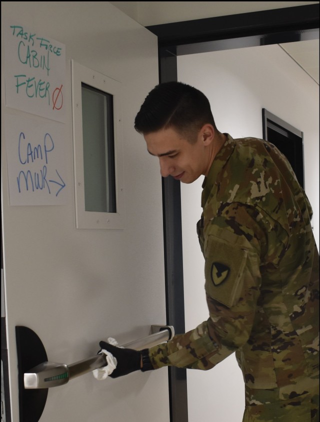 CHIÈVRES, Belgium – In this Army file photo, a member of Task Force Clean wipes a door down in the garrison headquarters. Task Force Clean is one of four task forces that protect the USAG Benelux community from the spread of COVID-19. (Courtesy photo)