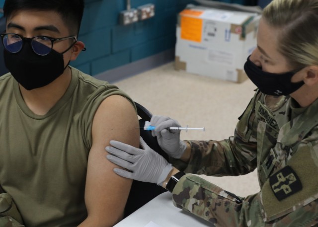 Army Reserve Capt. Candice Dominguez, deployed to Camp Arifjan, Kuwait, with the Fort Sam Houston, Texas, based 228th Combat Support Hospital, injects Spc. Johnny Valle, a native of Brooklyn, New York, deployed with the 5th Battalion, 7th Air Defense Artillery Regiment, with a COVID-19 vaccine as part of the restart of vaccine administration in theater, organized by 3rd Medical Command (Deployment Support). Valle, a Patriot fire control enhanced operator, said he was happy to get the vaccine now that it is available again. (U.S. Army photo by Staff Sgt. Neil W. McCabe)