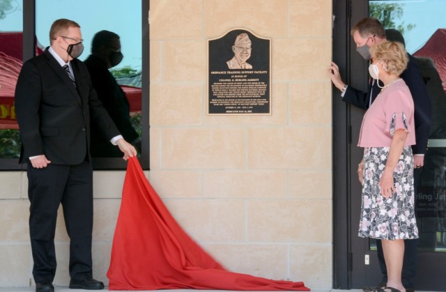 Ann Jarrett MacDonald, daughter of Col. George “Burling” Jarrett, along with her sons, retired Col. Michael Travis (right) and William Harrison Travis (left) unveil the plaque honoring Jarrett at the at the dedication ceremony of the Ordnance Training Support Facility May 14, 2021. The building was dedicated in honor of Jarrett, a member of the Ordnance Hall of Fame with a culmination of service to the ordnance community lasting nearly 50 years.