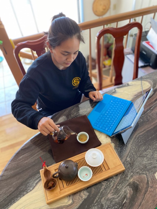U.S. Army 2nd Lt. Pauline Heng pours tea at her home while wearing a sweatshirt from Officer Candidate School, where she graduated in March 2021.