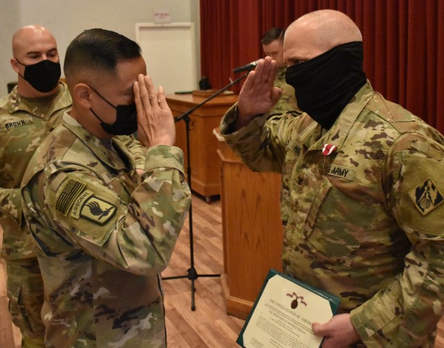 Command Sergeant Major Delfin Romani, Transatlantic Division CSM salutes Colonel John Haas Jr, after awarding him the Meritorious Service Medal at Camp Arifjan, Kuwait.