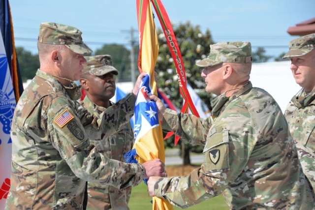 Gen. Ed Daly passes the U.S. Army Security Assistance Command flag to Brig. Gen. Garrick Harmon, officially transferring command of USASAC to Harmon from Brig. Gen. Doug Lowery (far right). USASAC Command Sgt. Major Sean Rice also participated in the May 17 ceremony held at the Army Materiel Command parade field.