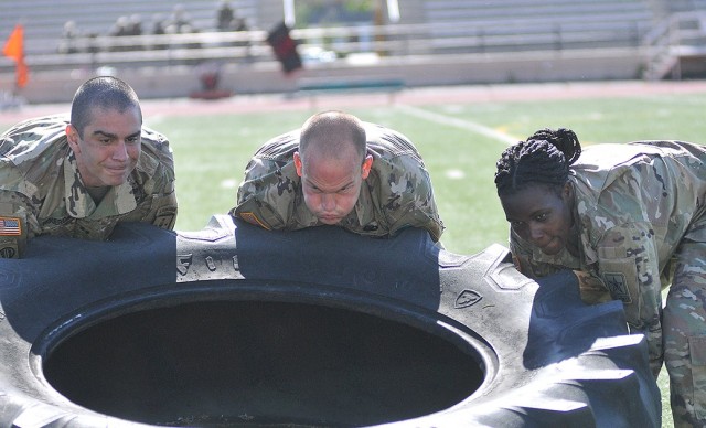 Capt. Jason Figueroa, Spc. James Petracca and Pvt. Evelyn Kitpoo, Charlie Company, 262nd Quartermaster Battalion, turn over a large tire during a race in which they had to repeat the action over several yards to reach the finish during May 14's...