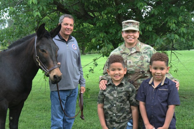 Staff Sgt. Lana Wheeler, transportation operations branch movements NCO, 1st Theater Sustainment Command, stands with her family next to the unit's mascot, Blackjack and his handler, at Fort Knox, Kentucky, May 14, 2021. Wheeler volunteered by...
