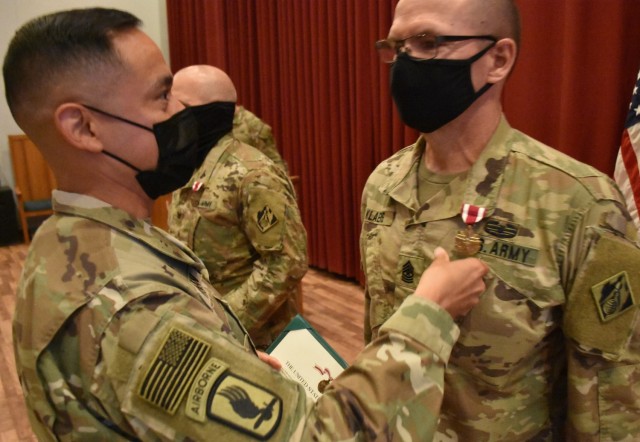 Command Sergeant Major Delfin Romani, Transatlantic Division CSM pins the Meritorious Service Medal on the lapels of Task Force Essayons outgoing Commander, Colonel John Haas, Jr. and outgoing Senior Enlisted Advisor, Sergeant Major William Klaers...
