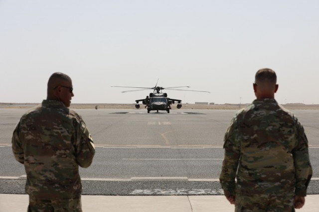 Task Force Phoenix Command Sgt. Maj. Refugio Rosas and commander Col. Alan Gronewold await the arrival of a party of visitors from Combined Joint Task Force - Operation Inherent Resolve on the flight line at Camp Buehring, Kuwait, before a Transfer of Authority ceremony.