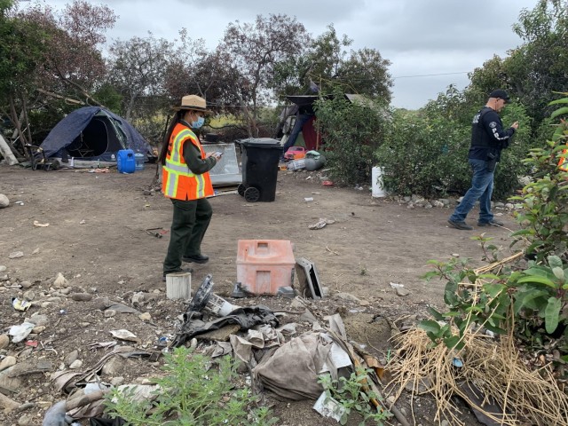 Park Ranger Annel Monsalvo, U.S. Army Corps of Engineers Los Angeles District, investigates one of dozens of abandoned campsites below the Santa Fe Dam, May 10, 2021, before crews arrive to clear out the debris.