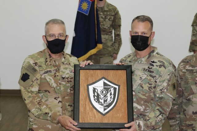 U.S. Army Col. Howard Lloyd, left, commander of the 28th Expeditionary Combat Aviation Brigade, presents a gift to Col. Alan Gronewold, commander of the 40th Combat Aviation Brigade, during a transfer of authority ceremony. The 28th ECAB formally transferred authority of their mission in the Middle East to the 40th CAB during a ceremony this week.