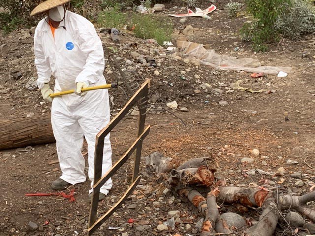 A U.S. Army Corps of Engineers Los Angeles District team member piles debris to be hauled away, May 10, 2021, in an abandoned homeless encampment.