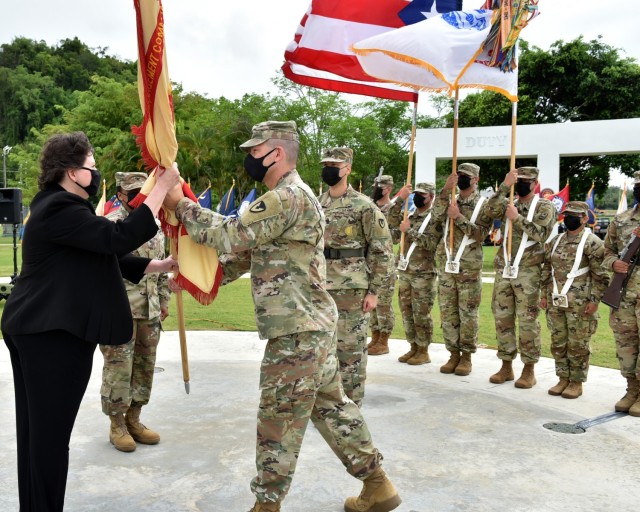 Outgoing Garrison Commander, Col. Joseph B. Corcoran III passes the garrison colors to IMCOM – Readiness Director and host for this ceremony, Brenda Lee McCullough, signifying his relinquishing command of Fort Buchanan.