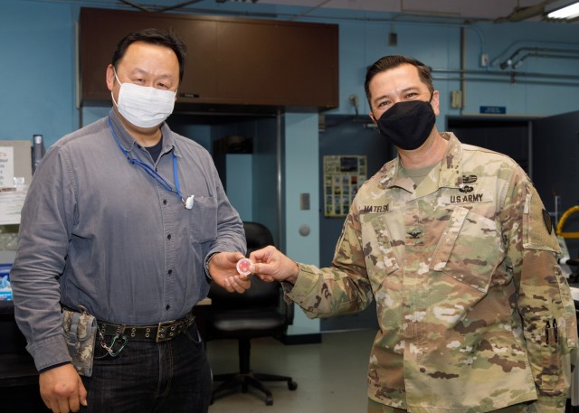 Col. Thomas Matelski, right, commander of U.S. Army Garrison Japan, presents Tohru Yamaguchi, a window clerk at the Camp Zama U.S. Post Office, with a commander’s “poker chip” at the facility on Camp Zama, Japan, May 14.