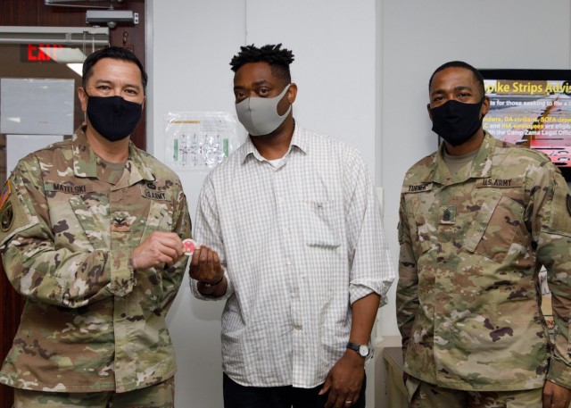 Col. Thomas Matelski, left, commander of U.S. Army Garrison Japan, and USAGJ Command Sgt. Maj. Justin Turner present Johnie Hickmon, who makes identification cards for the installation, with a commander’s “poker chip” at the facility on Camp...