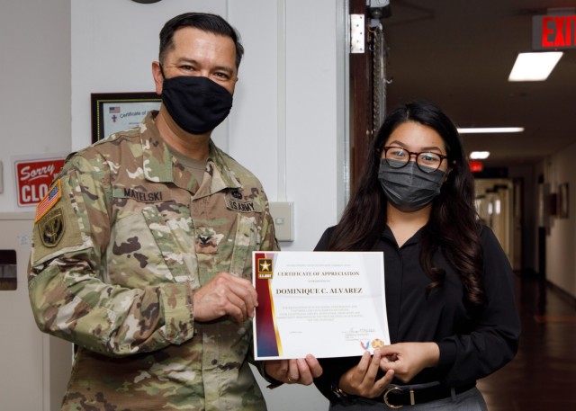 Col. Thomas Matelski, left, commander of U.S. Army Garrison Japan, presents Dominique Alvarez, a passport agent and personnel actions officer for the garrison’s Directorate of Human Resources, with a commander’s “poker chip” at the...