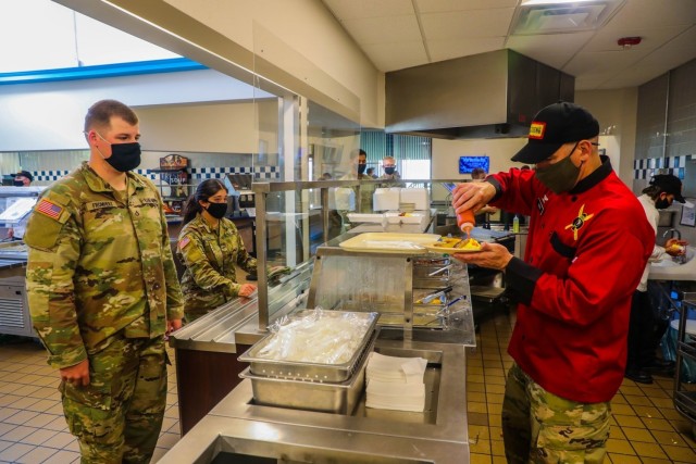 Col. Robert Born, commander, Brigade Combat Team “Bastogne”, 101st Airborne Division (Air Assault), right, pours condiments on eggs for Pfc. Alec Fromherz, infantryman, ABU Company, 1st Battalion 327th Infantry Regiment “Above the Rest,” left, during breakfast service May 14 in Snipes Dining Facility on Fort Campbell, Kentucky. Culinary Experts in Snipes Dining Facility conduct a contact free breakfast service by pouring condiments and serving each food item to over 3,000 Soldiers in the brigade every day to mitigate the spread of COVID-19 ensuring the health and welfare of the unit.