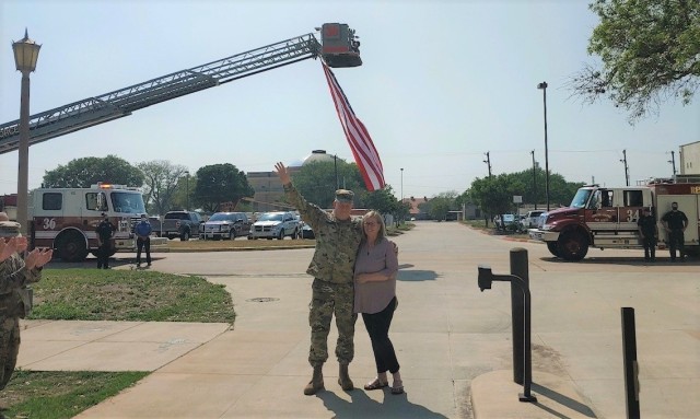 MG Timothy McGuire, Deputy Commanding General of U.S. Army Installation Management Command, and his wife, Suzie, stop in the shadow of a flag provided by JBSA first responders to give a final wave to the hundreds of Army professionals who gathered for a fond send-off from IMCOM HQ on April  9, 2021. McGuire is retiring from the Army after a distinguished 34-year career in a ceremony on May 28, 2021, at the Fort Sam Houston Theatre.
