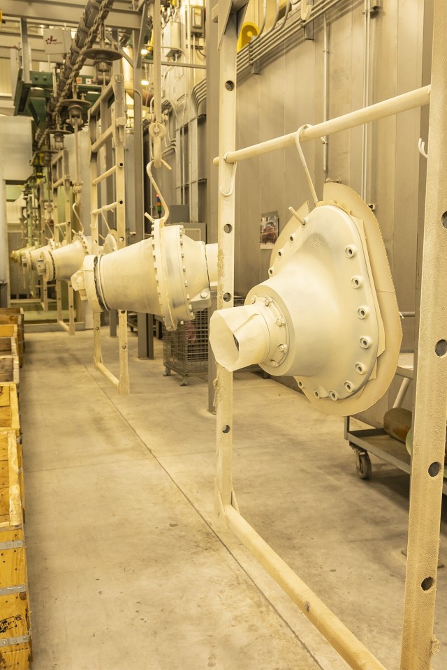 A row of final drives for the M1 Abrams hang on a paint conveyor where they await a final coat of paint.