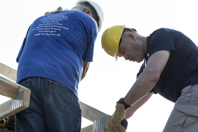 U.S. Army Reserve Command Sgt. Maj. Steven Gardin, senior enlisted leader for the Mobilization Demobilization Operations Center from the 2-381st Training Support Battalion, 120th Infantry Brigade, Division West, assists another volunteer with fastening a piece of  wooden roof frame on to new house construction during a Habitat for Humanity housing project in Waco, Texas, May 16, 2021.  Gardin, along with other Army Reserve Soldiers on the MDOC team used this volunteer opportunity to frame a creative way for team and leadership building while also supporting the local community. (U.S. Army Photo by Staff Sgt. Erick Yates)