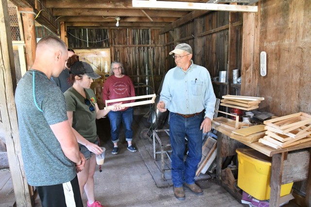 Rolly Churchill talks about the different types of hive frames that serve as the structure for bees to build the honeycomb. Veterans and active-duty service members toured the bee farm and workshop at Churchill Farms in Watertown on May 24, and...