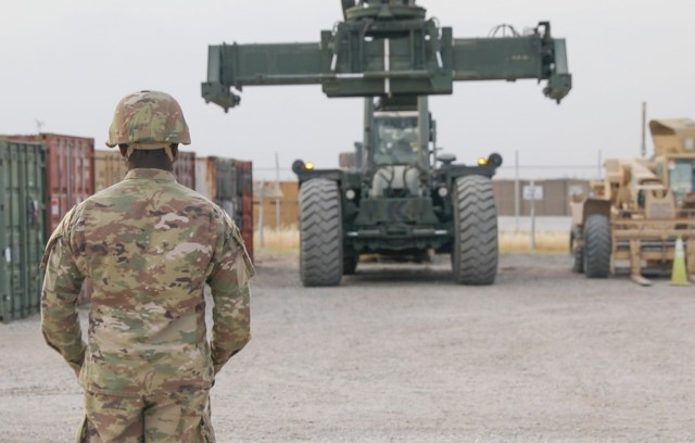 Sgt. Karlos Golightly, 221st Ordnance Company, 541st Combat Sustainment Support Battalion, 310th Expeditionary Sustainment Command, guides a rough terrain container handler (RTCH), in the forward logistics element&#39;s container yard at Erbil Air...