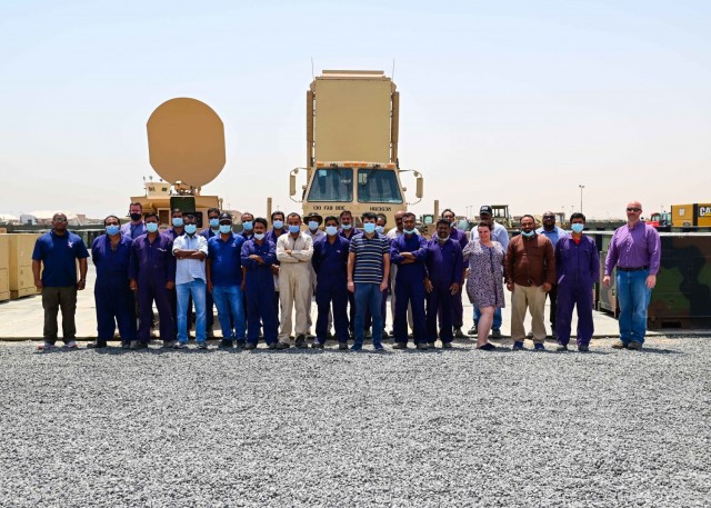 The Communications-Electronics Command Regional Support Center’s civilian team at the 401st Army Field Support Brigade gathers in front of various generators, a Trojan AN/TSQ-226B(V) Communications system, and a AN/TPQ-53 Radar at Camp Arifjan, Kuwait, May 20. The Camp Arifjan RSC’s civilian workforce worked tirelessly to rapidly establish in-theater power generator rebuild and exchange programs.