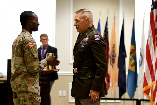 Staff Sgt. Donnell Stallworth from the salute battery presents newly promoted Brig. Gen. Charles Lombardo, Combined Arms Center-Training Deputy Commanding General, with an artillery canister during Lombardo’s promotion ceremony May 28, 2021 at the Frontier Conference Center, Fort Leavenworth, Kan. The canister represents the first round fired in Lombardo’s honor as a general officer. Photo by Tisha Swart-Entwistle, Combined Arms Center-Training.