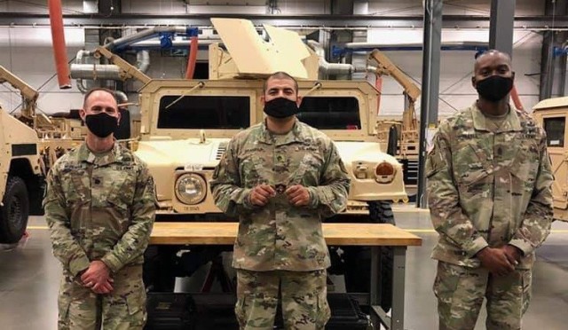 Leaders of the 16th Ordnance Battalion -- Lt. Col. Aaron Workman, left, and Command Sgt. Maj. Christopher Reaves, right – pose with Staff Sgt. Gustavo Brambila after presenting him with a coin of excellence for his commitment to students and the “Maintainer” team.