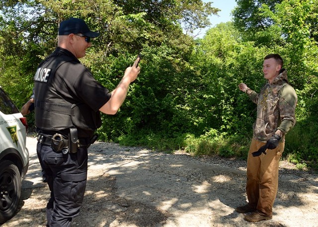 Department of the Army Civilian Police Officer James Callaway takes a photograph of "escaped inmate" role-player 1st Lt. Daniel Loomer, commander of Headquarters and Headquarters Detachment, 15th Military Police Brigade, after Loomer emerged from...