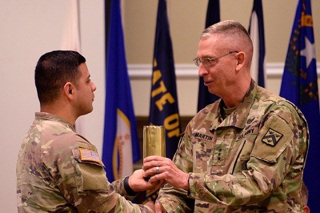 Staff Sgt. Manuel Vera, 500th Military Police Detachment, Special Troops Battalion, presents a spent shell casing to incoming Combined Arms Center and Fort Leavenworth Commanding General Lt. Gen. Theodore Martin during Martin's change of command...
