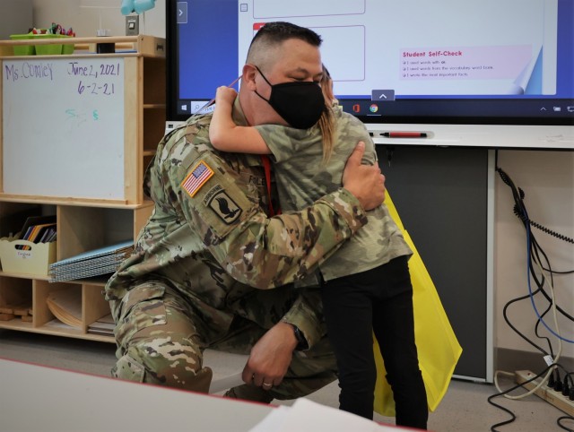 Kingsolver first-grader Avery Brown hugs Garrison Command Sgt. Maj. William Fogle, who presented her with several coins in front of her class June 3 in recognition for her efforts raising funds for the 2021 Army Emergency Relief campaign.