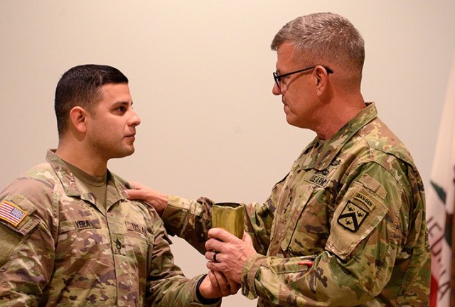 Staff Sgt. Manuel Vera, 500th Military Police Detachment, Special Troops Battalion, presents a spent shell casing to outgoing Combined Arms Center and Fort Leavenworth Commanding General Lt. Gen. James Rainey during Rainey's change of command...