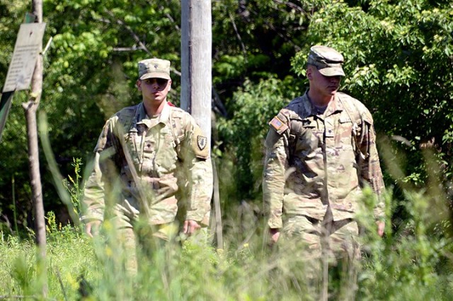 Spc. David Barajas and Spc. Rhett Magee, both of Headquarters and Headquarters Company, U.S. Disciplinary Barracks, search an area behind the Old USDB looking for footprints, food wrappers, clothing or anything else that might indicate someone had...