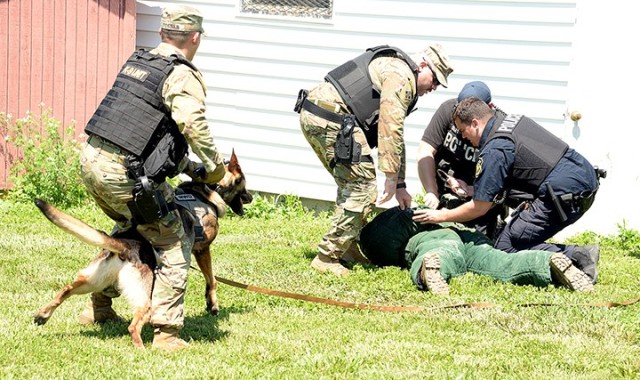 Spc. Richard Tossas, 67th Military Police Detachment (Military Working Dog), Special Troops Battalion, holds MWD Hamed, a 6-year-old German shepherd-Belgian malinois, as acting kennel master Staff Sgt. Hector Rodriquez, 67th MP Detachment, and...