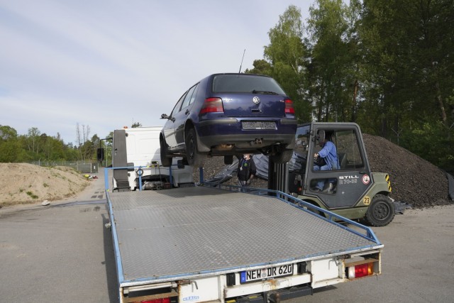 A forklift raises a vehicle onto an FMWR tow truck from the abandoned vehicle lot to a location to be salvaged and sold as an initiative to rid the installation of abandoned vehicles.