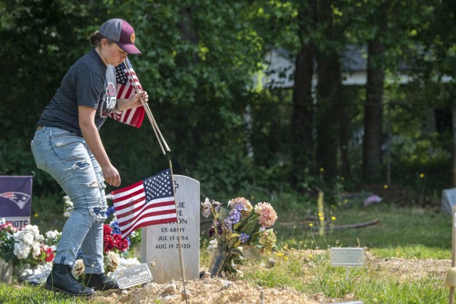 First Lt. Jessica Hindman, officer in charge of the Memorial Day Ride event, places flags at the Gates of Heaven Cemetery in Columbia May 28.