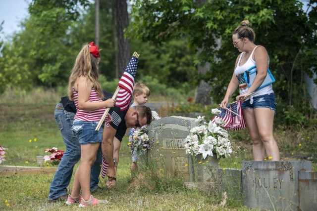 A Soldier and his family place flags at the Gates of Heaven Cemetery in Columbia during the 165th Infantry Brigade Memorial Day Ride event May 28.