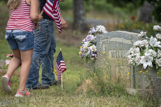 A Soldier and his family place flags at the Gates of Heaven Cemetery in Columbia during the 165th Infantry Brigade Memorial Day Ride event May 28.