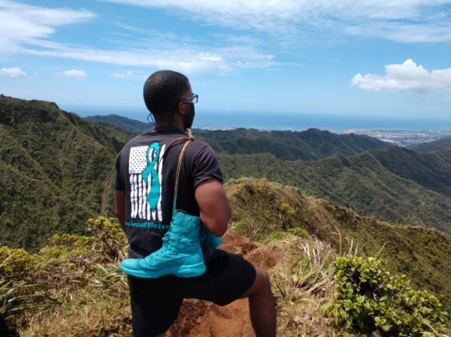 Carrying his teal-colored boots in honor of SAAPM, Staff Sgt. Demarco Pennington, of Alpha Company, 307th Expeditionary Signal Battalion, pauses to take in the view atop the “Stairway to Heaven” on the island of Oahu, Hawaii, during a group hike in April of 2021 to honor survivors of sexual assault. (Photo courtesy of Staff Sgt. Demarco Pennington, 307th Expeditionary Signal Battalion)