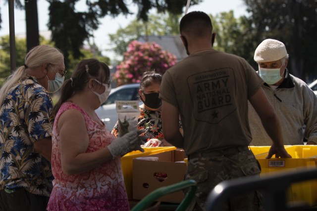 A Washington Army National Guard Soldier, assigned to Joint Task Force Steelhead, the Washington National Guard&#39;s COVID-19 response force, works with volunteers to distribute fresh produce at the Kent Food Bank, June 22, 2021, in Kent, Wash....