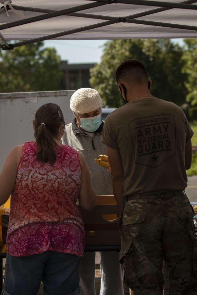 A Washington Army National Guard Soldier, assigned to Joint Task Force Steelhead, the Washington National Guard&#39;s COVID-19 response force, works with volunteers to distribute nonperishable groceries at the Kent Food Bank, June 22, 2021, in...