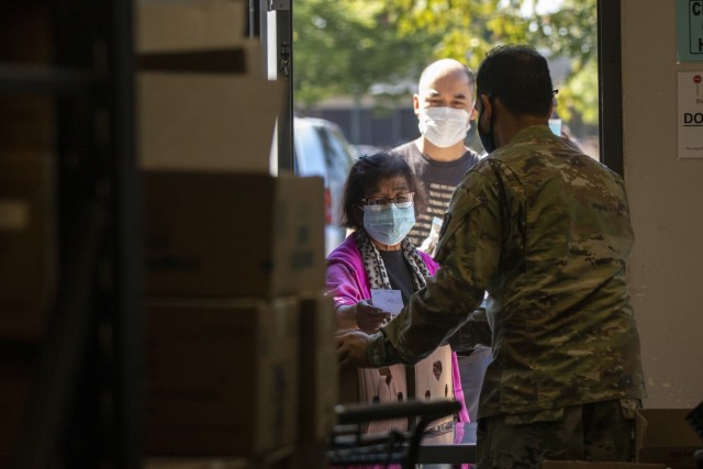A Washington Army National Guard Soldier, assigned to Joint Task Force Steelhead, the Washington National Guard&#39;s COVID-19 response force, works with volunteers to distribute nonperishable groceries at the Kent Food bank, June 22, 2021, in...