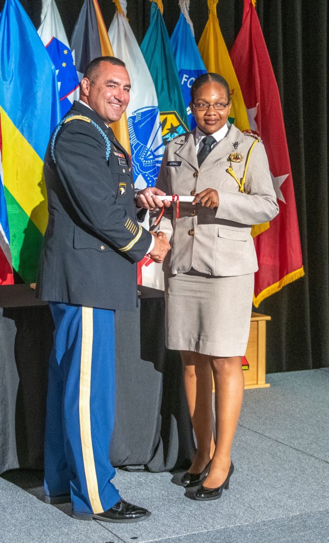 (FORT BENNING, Ga) - Col. James T. McGahey, 199th Infantry Brigade commander, presents the Army school&#39;s badge to Capt. Magon Aspinall,  Belize Defence Force, marking her completion of the Maneuver Captains Career Course. Twenty-Four International Military Students for 16 partner nations completed the MCCC and received their school badge in a ceremony on June 10, 2021 at the Bibb Mill Event Center.  McGahey was the guest speaker.  (U.S. Army photo by Patrick Albright, Maneuver Center of Excellence, Fort Benning Public Affairs)